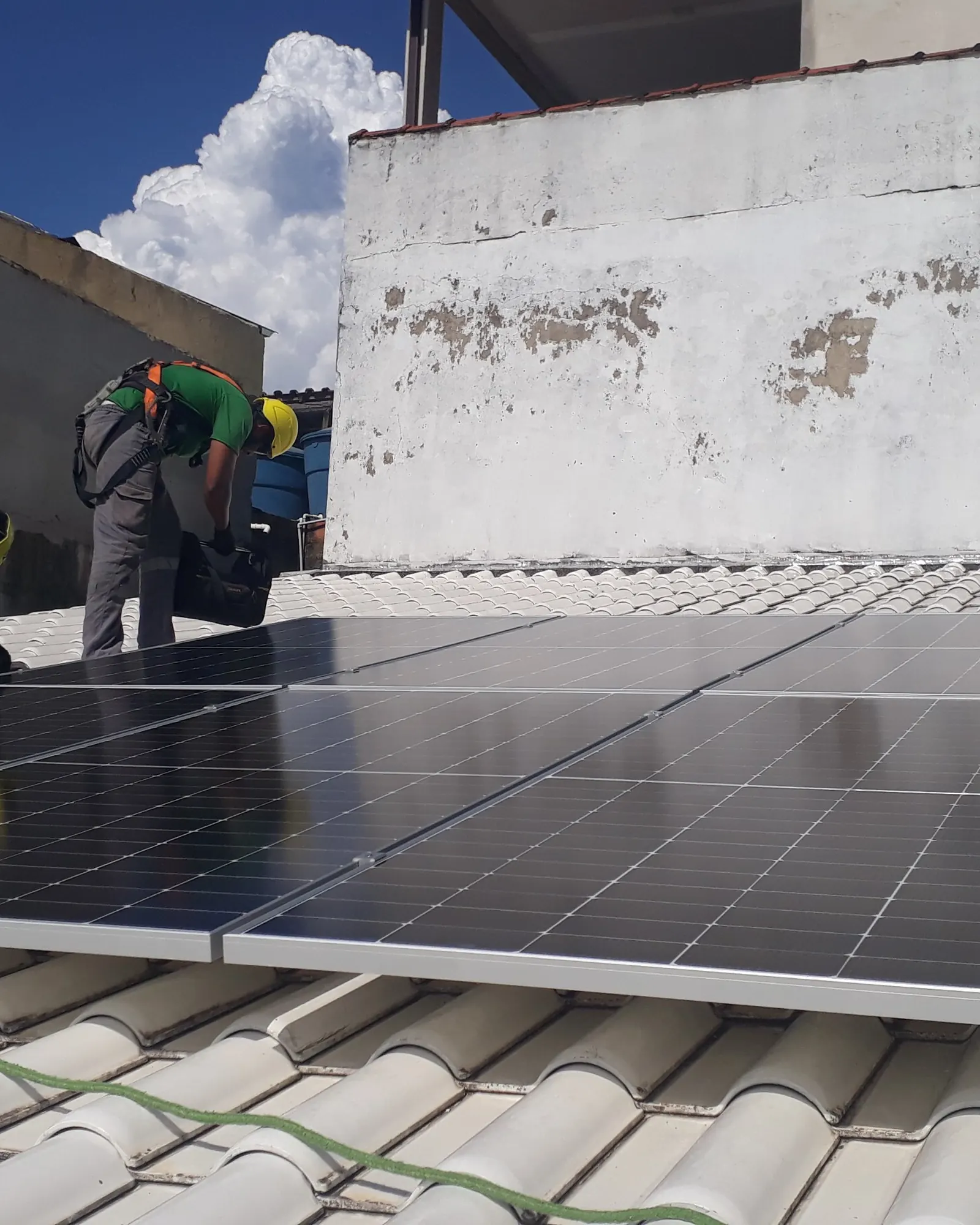 Técnicos montando módulos monocristalinos sobre telha cerâmica branca